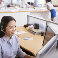 Smiling Asian woman working in a call centre, elevated view